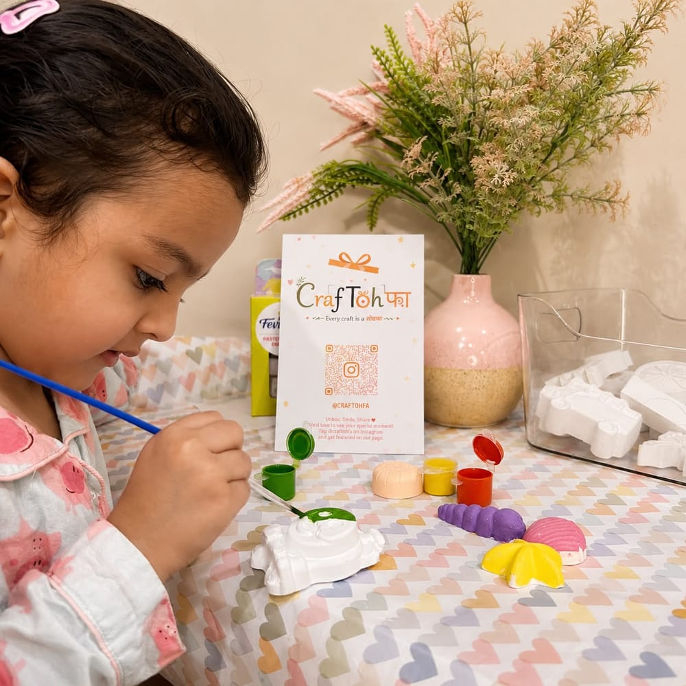 A child leaning over a table, brush in hand, painting a plaster piece beside a row of paint pots