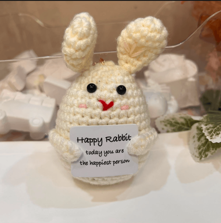 A cream hand-crocheted bunny keychain holding a card reading "Happy Rabbit, today you are the happiest person"